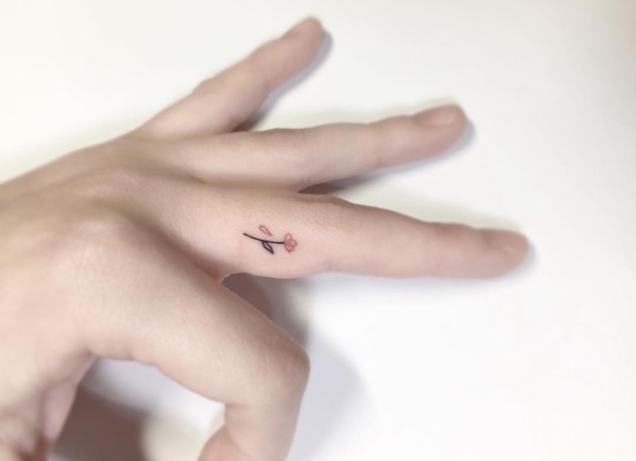 petit tatouage discret réalisés sur le côté du doigt représentant une fleur colorée, idée de tattoo doigt femme