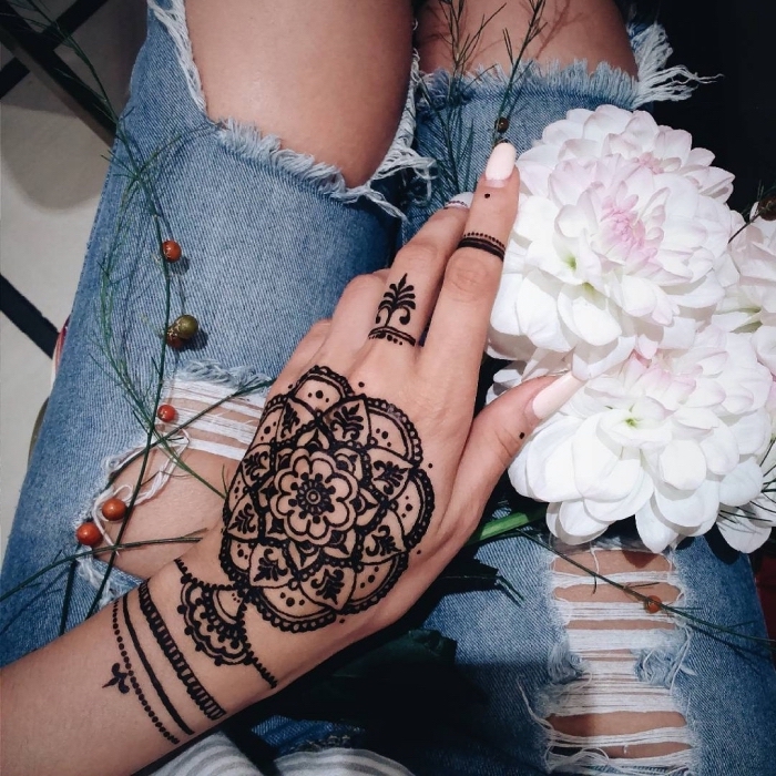 tattoo doigt façon bague qui s'assortit avec le mandala fleur tatoué sur la main
