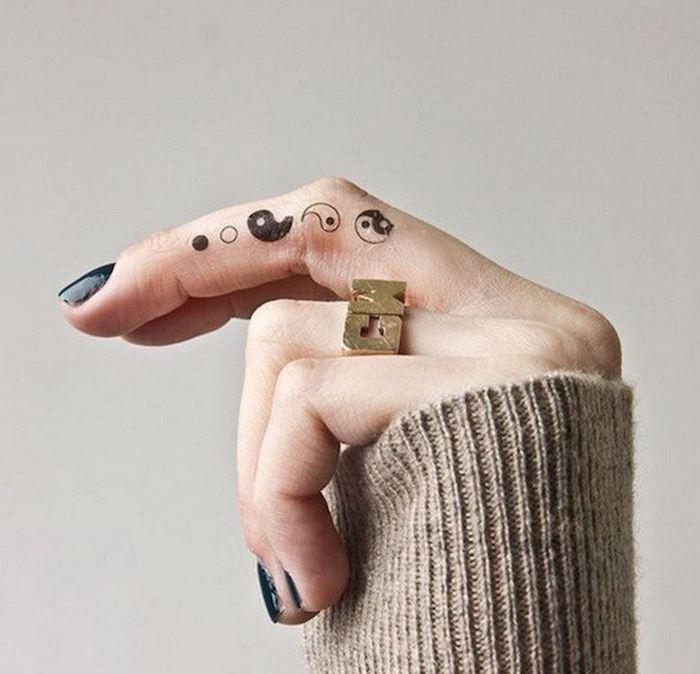 petit tatouage sur le doigt représentant les symboles yin et yang réalisés sur le côté du majeur