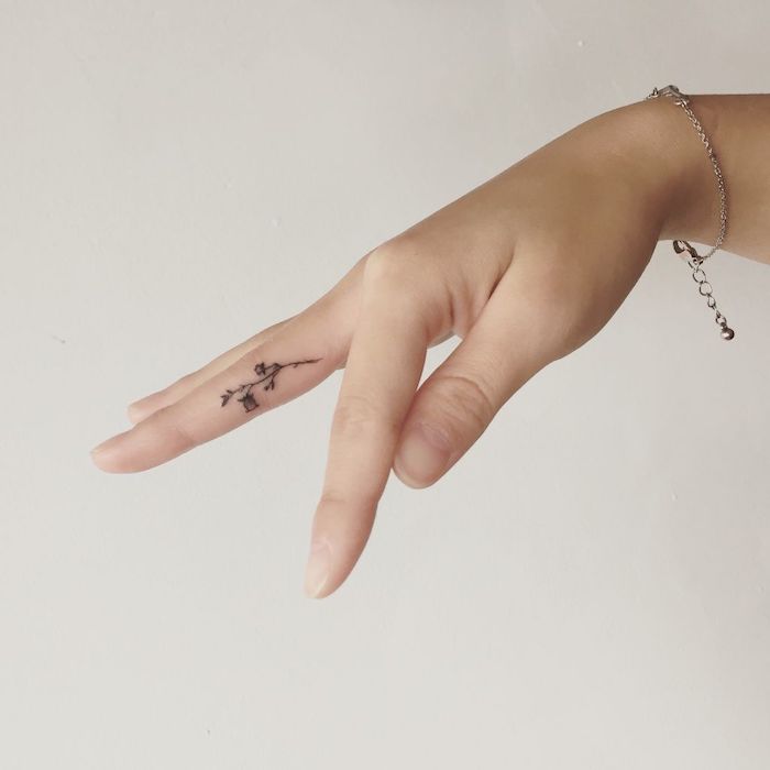 petit tatouage sur le côté du doigt majeur, tatouage de fleur au design subtil et féminin