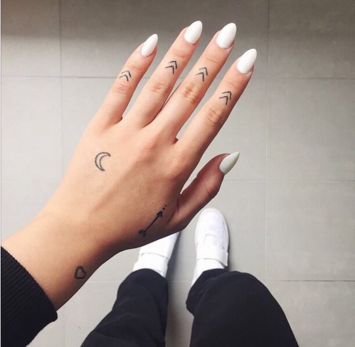 petites flèches tatouées sur les doigts, tatouage sur les doigts à motifs tribaux minimalistes