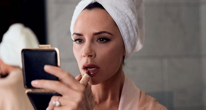 Victoria Beckham en train de se maquiller pour illustrer le lancement de sa propre marque de produits de beauté 