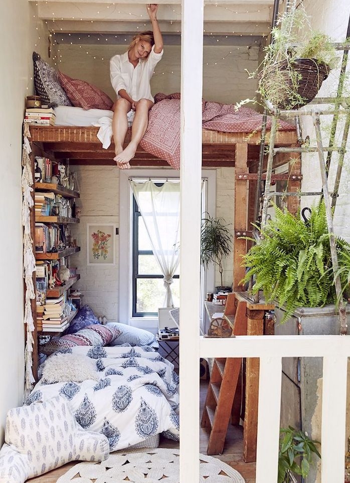 deco cocooning de petit studio avec lit bois en hauteur au dessus d un coin cosy avec canapé par sol et bibliothèque de livres