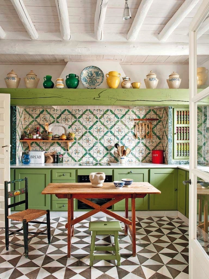 une cuisine de style campagne équipée d'une credence carreaux ciments à motifs vintage en vert et blanc qui s'harmonisent avec les placards couleur vert anis