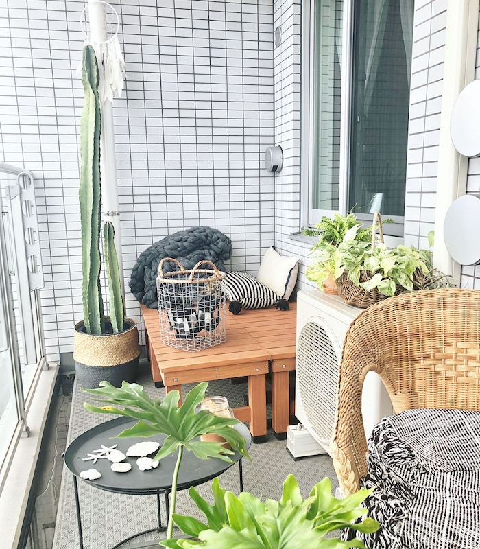 deco terrasse et balcon revêtu de carrelage blanc avec des bancs de bois et chaise de rotin, table basse noire, plantes exotiques d exterieur, tapis gris