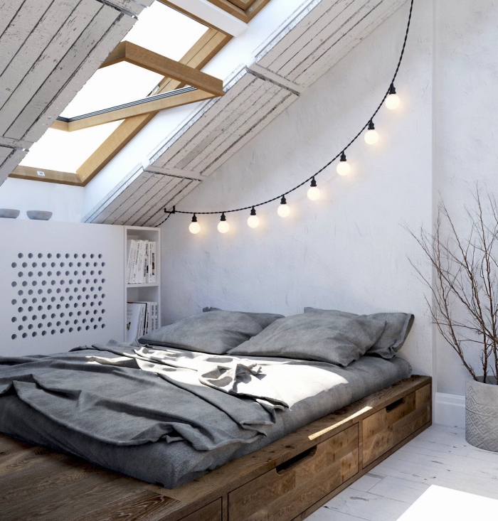 une chambre à coucher mansardée de style minimaliste avec lit bas à tiroirs intégrés et un meuble sous pente fonctionnel posé à côté