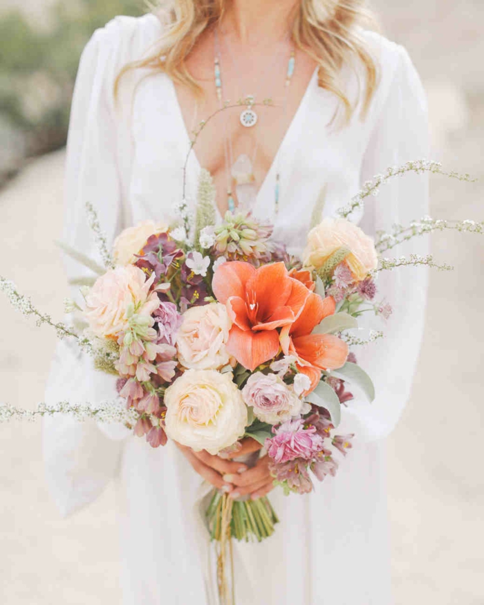 jolie composition florale mariage, lys orange, roses couleur crème, fleurs mauves, décolleté triangle et bijux bohèmes