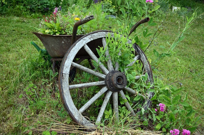 brouette métallique vintage comme grand pot de jardin et roue de charrete, décoration jardin rustique, pelouse verte