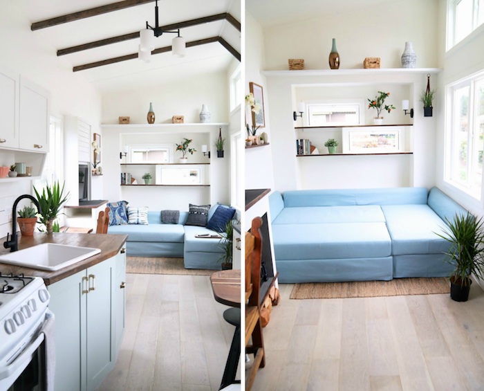 canapé et lit deux en un design modulable en couleur bleue, murs blancs, petites poutres apparentes marron, étagères ouvertes, cuisine miniature bois et bleu