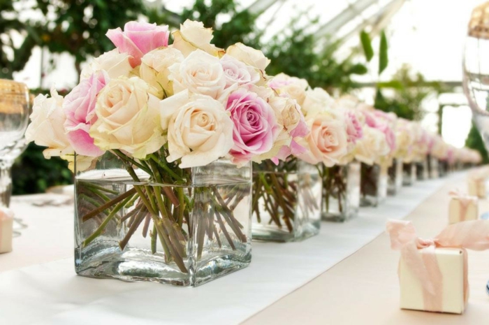 grands bocaux en verre remplis de roses, chemin de table blanc, petits cadeaux sur la table de mariage