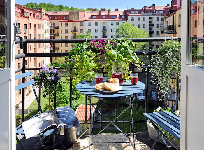 table et chaises de balcon sur un sol de terrasse avec tapis rond, modele de balcon fleuri avec belle vue sur bâtiments anciennes
