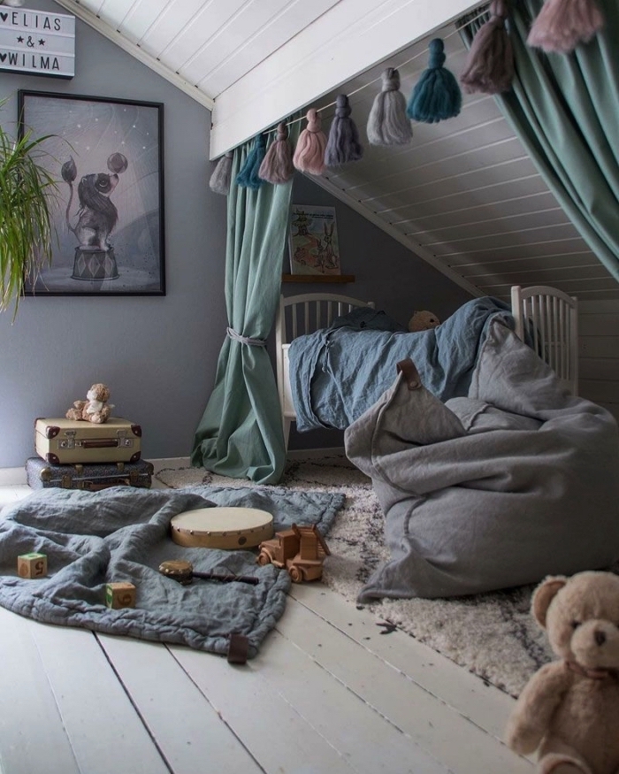 une chambre d'enfant aménagée sous pente avec un lit posé sous pente derrière des rideaux