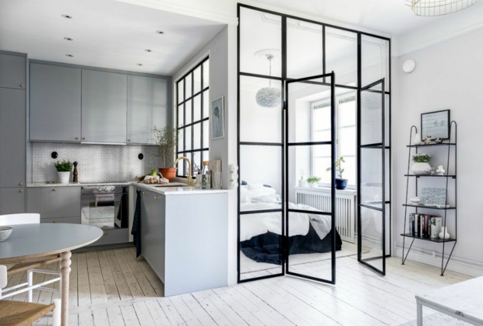 appartement style scandinave, planches en bois blanc, table ovale, placards de cuisine gris, porte d'artiste, étagère autoportante