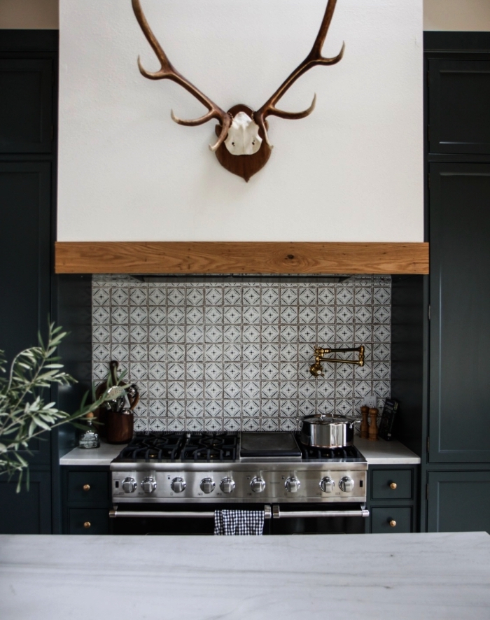 une belle crédence cuisine carreaux de ciment gris clair en petit format posée derrière la plaque de cuisson qui contraste avec les meubles de cuisine bleu nuit