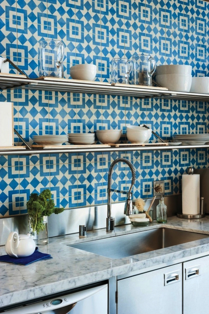 une crédence cuisine carreaux de ciment graphiques en bleu sarcelle qui réchauffe l'ambiance de cette cuisine en inox et marbre