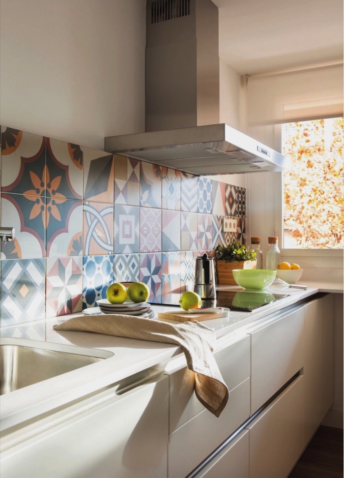des carreaux de ciment patchwork posés en crédence qui apportent du dynamise au décor monochrome de la cuisine aux meubles blancs 