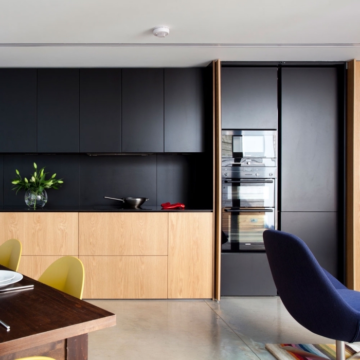 décoration cuisine moderne en noir et bois, meubles haut de cuisine en noir mate, rangement fermé sans poignée