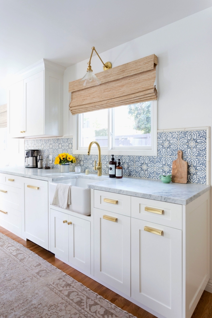 une credence carreaux de ciment lumineuse aux motifs anciens floraux en bleu clair dans une cuisine blanche aux accents laiton