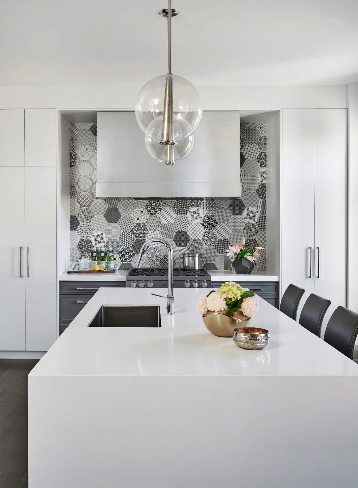 une credence carreaux de ciment hexagonaux de style patchwork en gris clair qui apporte une touche d'élégance dans la cuisine monochrome blanche