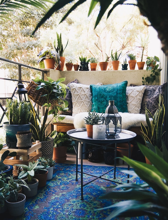 deco boheme chic de balcon cosy avec canapé décoré de plaid et coussins colorés, tapis oriental, petit jardin exterieur de plantes grasses, table basse ronde