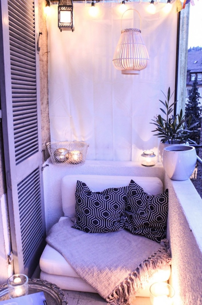idee d aménagement petit balcon avec petit fauteuil par sol décoré de coussins noir et blanc et couverture grise, deco de bougeoirs et lanterne suspendue