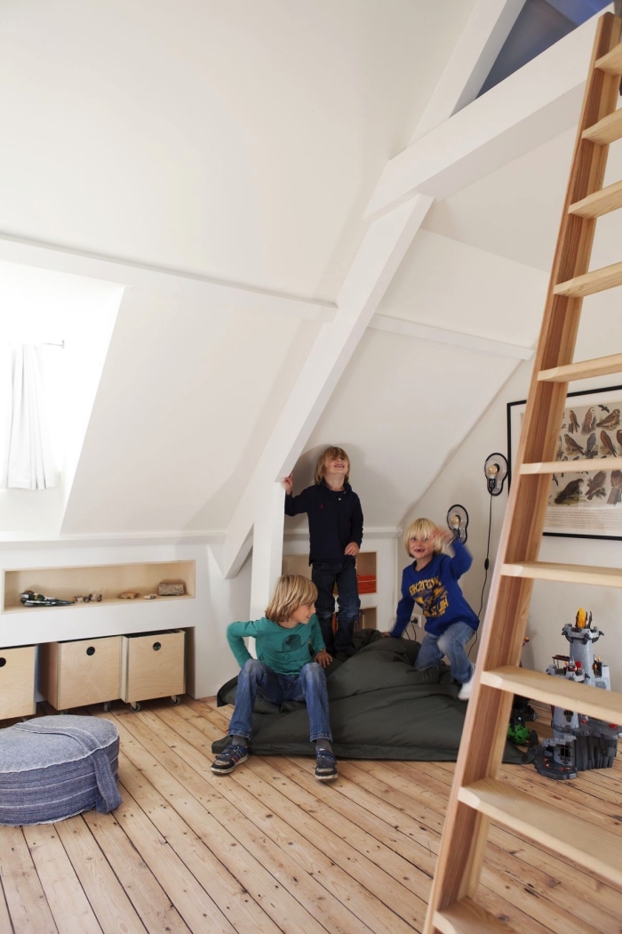 une chambre d'enfant mansardée de style scandinave avec etagere sous pente gain de place et un lit cabane aménagé sous les combles, espace de jeu dans les combles