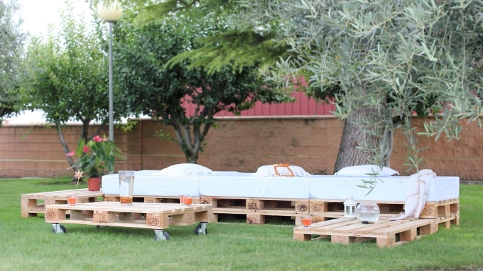 diy canapé palette fait main couvert de matelas blanc et de coussins décoratifs, modèle de table basse de jardin avec roulettes