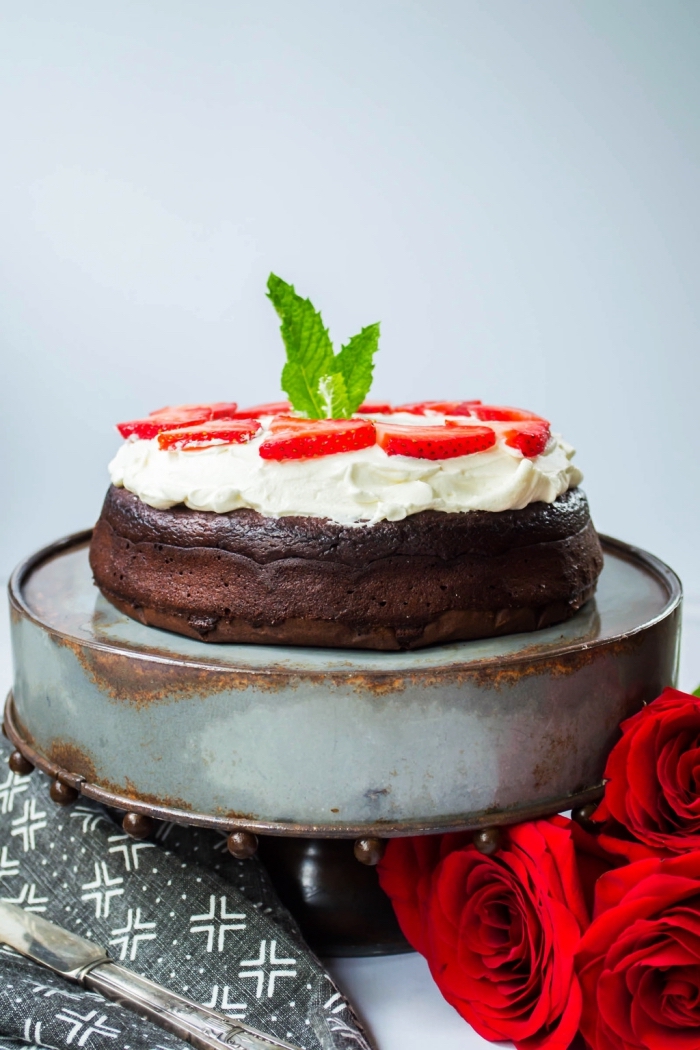 recette originale de gateau au chocolat sans farine nappé de crème fouettée et décoré de tranches de fraises