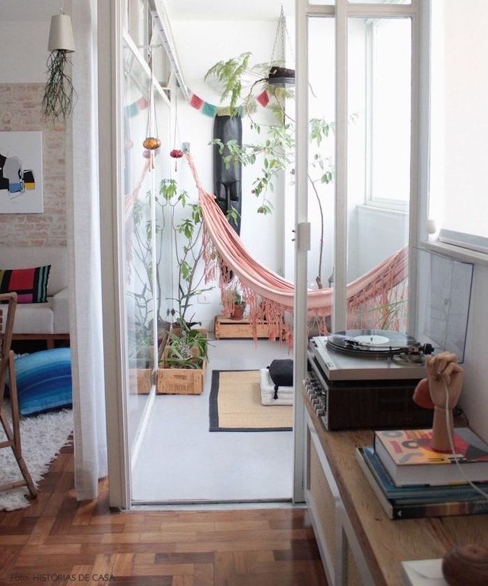 deco hippie chic sur un balcon tout petit avec hamac exterieur rose, plantes vertes, petit tapis, paroi vitrée terrasse