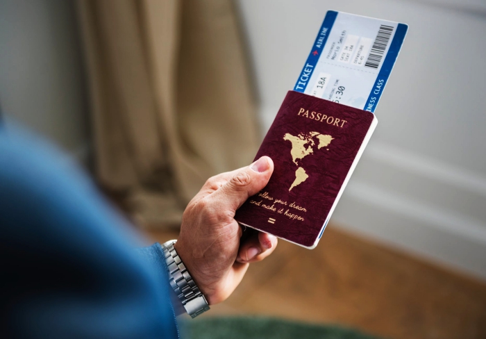 un homme tenant un passeport avec un billet d'avion, conseils pratiques pour mieux organiser son vol, se renseigner sur les documents à fournir