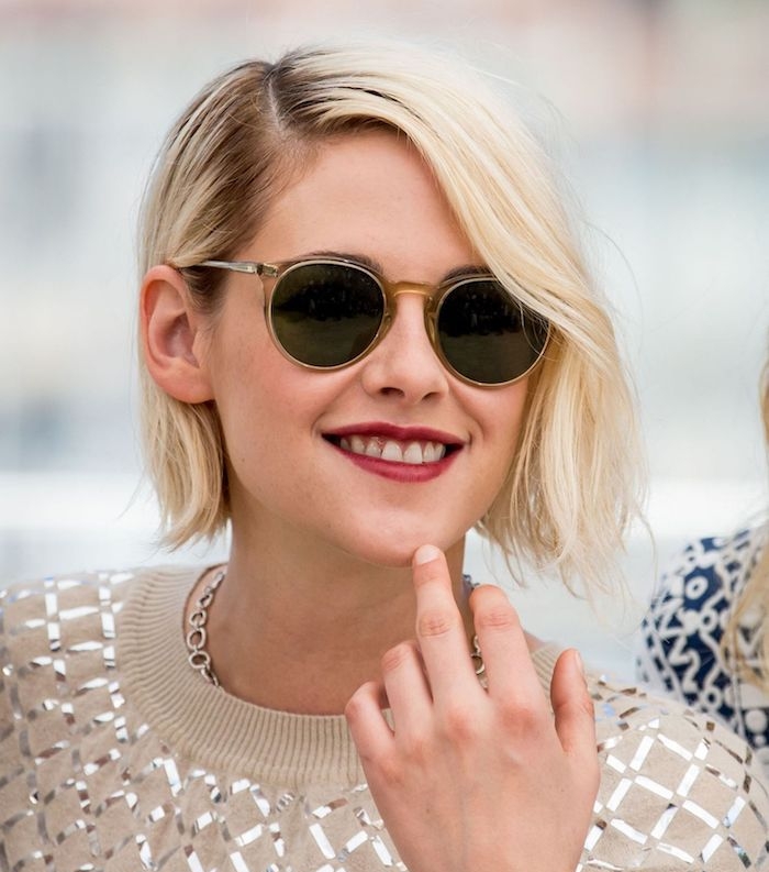 coiffure avec raie sur le côté de cheveux en carré flou, lunettes de soleil femme noires, coloration blond polaire