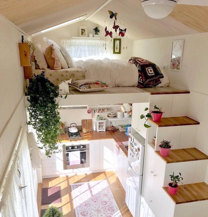 lit sur un deuxième étage auquel mène un escalier un bous, amenagement coin nuit sous pente, cuisine compacte en bois et blanc