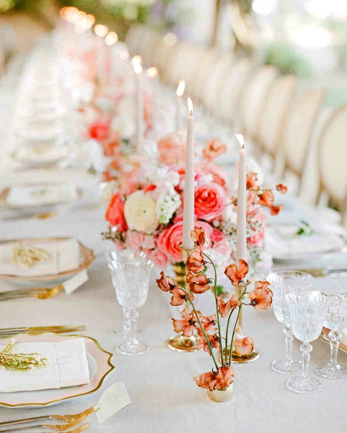 table de mariage blanche, roses magnifiques, bougies allumées blanches, assiettes aux rebords dorés