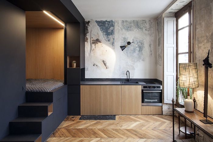 aménagement studio 20 m2 avec cuisine noire et bois et coin chambre à coucher sur estrade niche noire, parquet bois clair