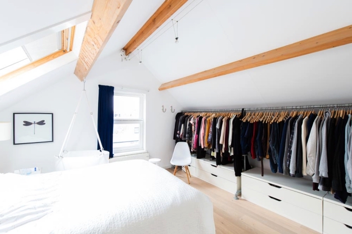 une chambre à coucher mansardée de style scandinave minimaliste avec dressing sous pente ouvert qui suit la pente du toit