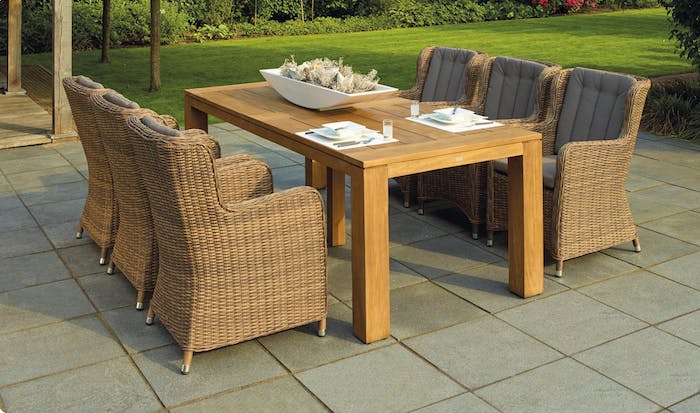 fauteuils en rotin et table en bois, le parfait coin salle à manger sur une terrasse extérieure à coté d un jardin avec gazon