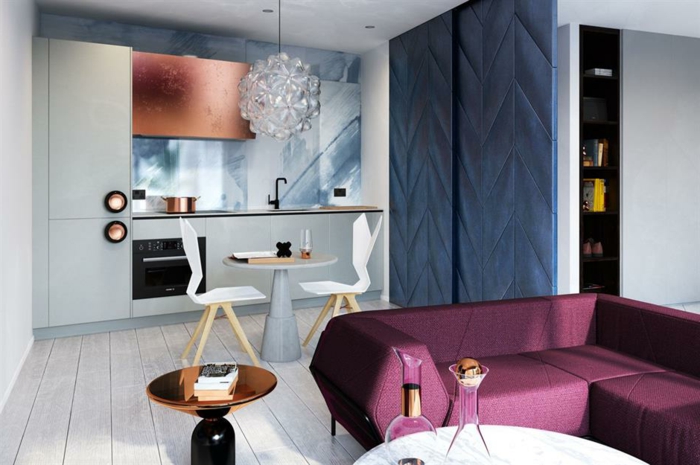 sofa pourpre, plancher blanc, lampe en cristal, petite cuisine moderne, armoire suspendue cuivrée