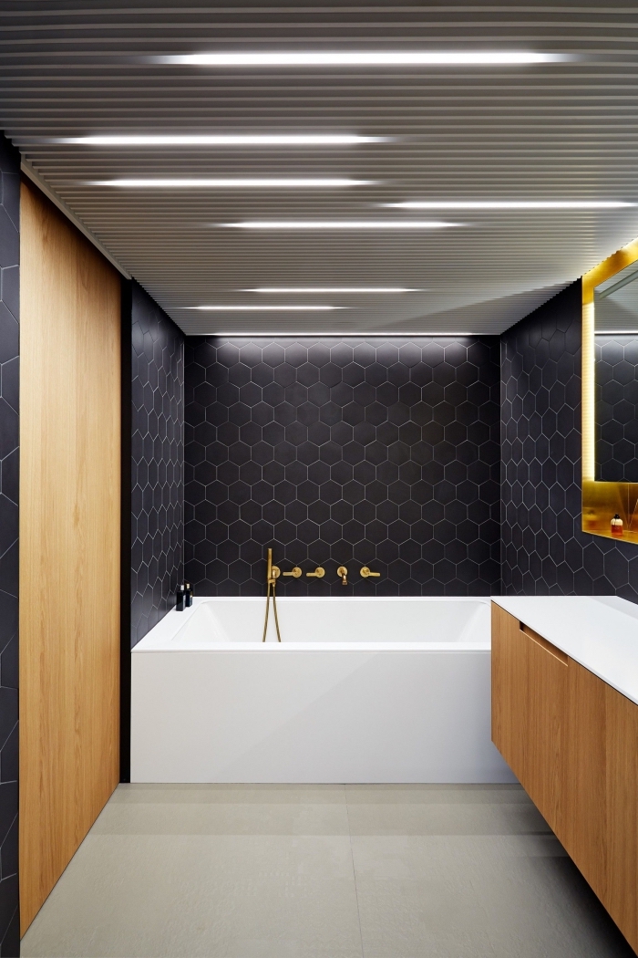 panneau décoratif mural à imitation bois, aménagement salle de bain avec baignoire, choix carrelage moderne aux motifs hexagonaux en gris foncé