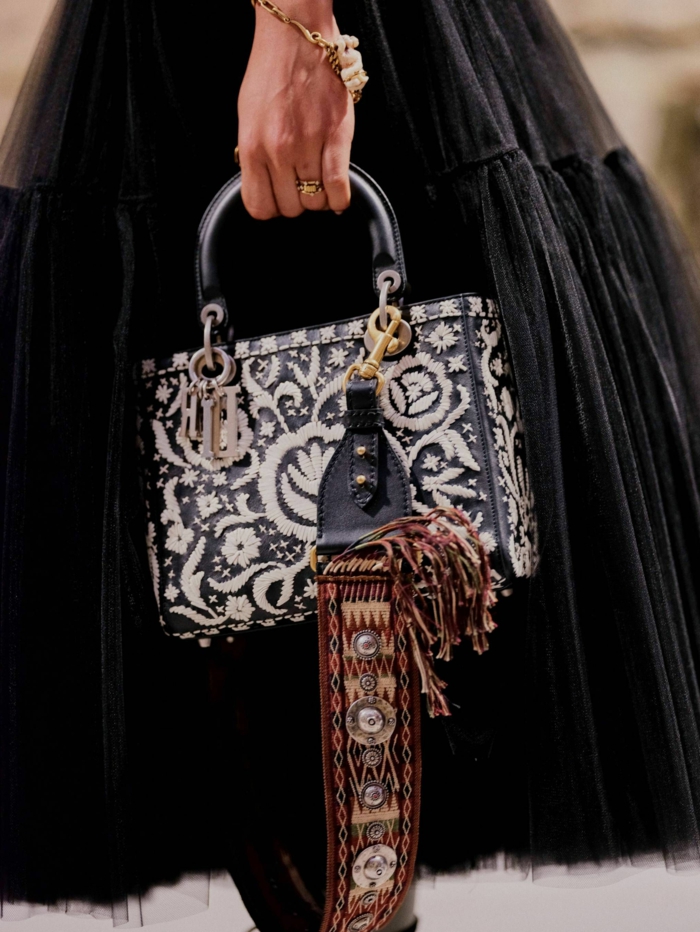 longue jupe noire, sac texturé avec figures floraux, bracelet en or, poignée statement noire