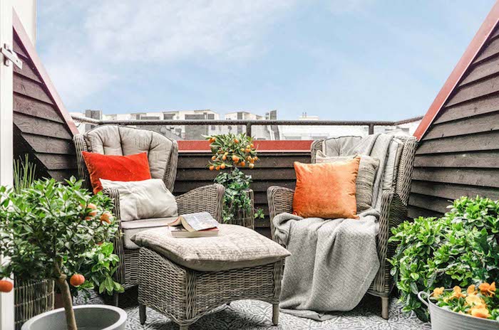 arbres orangers sur une terrasse avec des fauteuils et table tressés, plantes tropicales sur une terrasse, sol gris et blanc