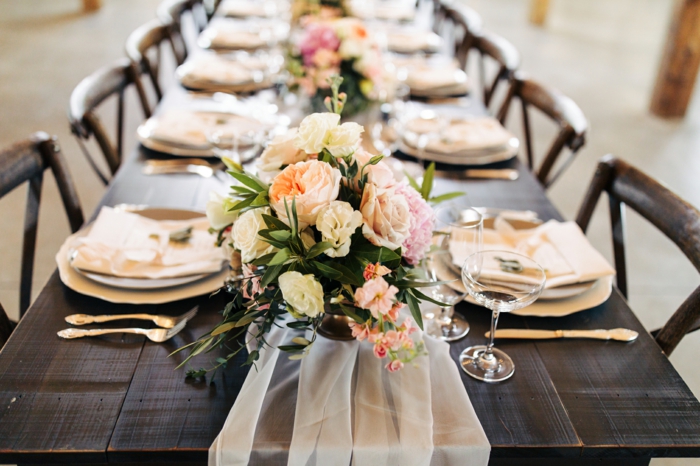 table de mariage en bois foncé, assiettes couleur ivoire, chemin de table en tulle blanc 