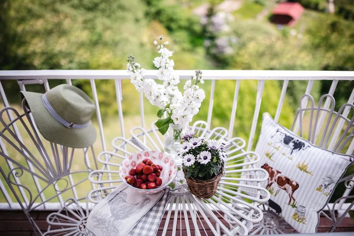 table et chaises blanches en metal sur un tout petit balcon avec decoration fleurie, ambiance relaxante et cosy