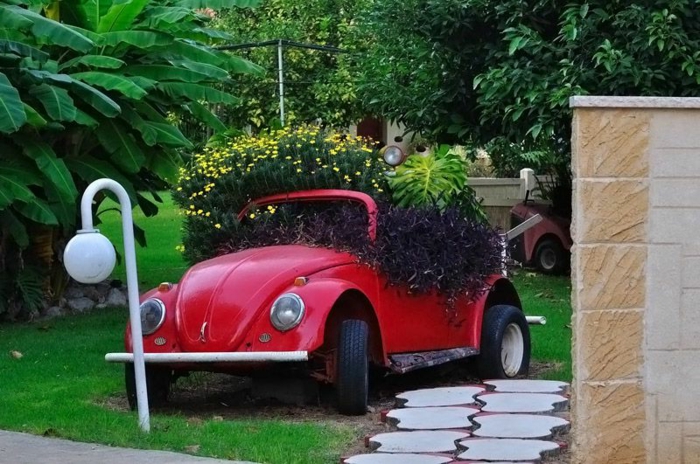 deco exterieur pour un grand jardin, lampes de jardin, pelouse verte, ancienne voiture rouge avec fleurs plantées