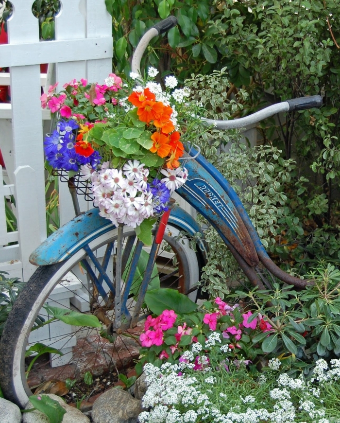 verdure abondante et bicyclette bleue, pots de fleurs sur la corbeille du vélo, déco jardin fleurie vintage