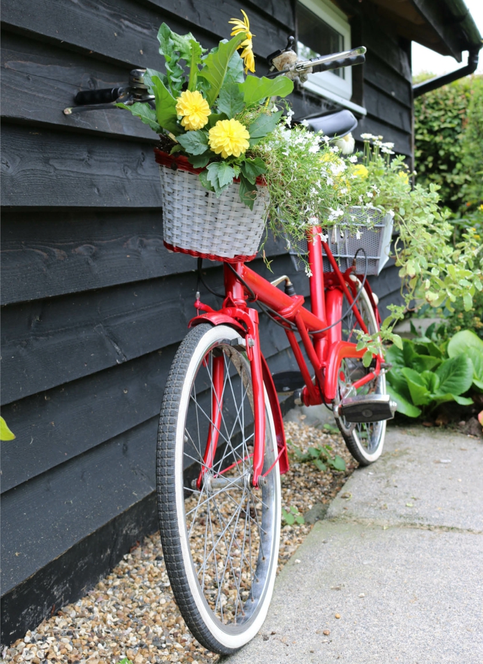 vélo vintage rouge utilisé comme support pour pots de fleurs, maisonnette en bois, decor jardin créatif