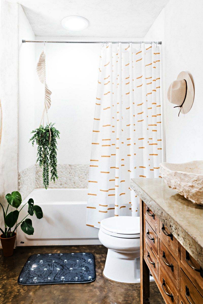 idée d'aménagement d'une petite salle de bain de 5m2 dans un style nature, baignoire-douce avec crédence en galets décorée d'une plante suspendue, meuble sous vasque chiné avec une vasque à poser en pierre naturelle