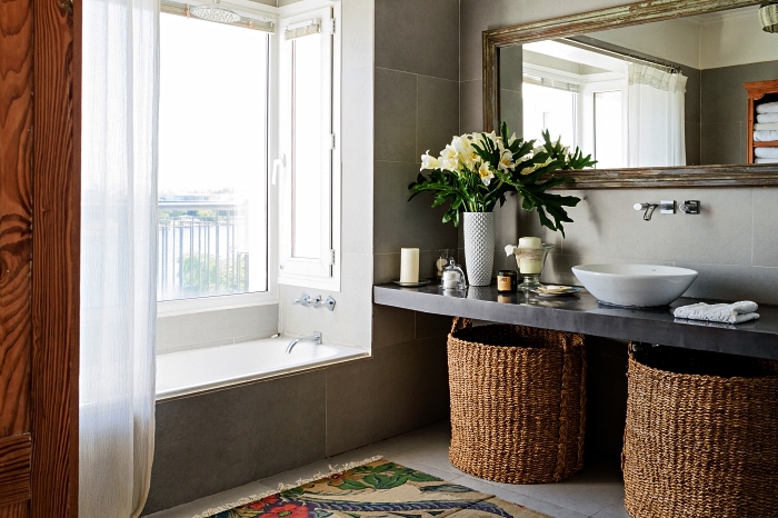 salle de bain nature et rustique avec plan vasque en béton, une vasque à poser ovale et de gros paniers en fibres naturelles