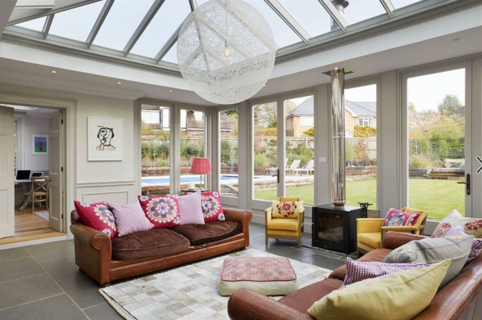 construire une veranda contemporaine, sofas marron et plueurs coussins, tapis blanc, toiture en fenêtres