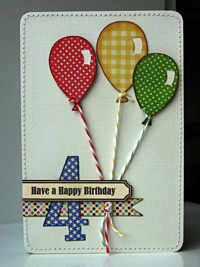 une carte anniversaire enfant en papier texturé décorée de petits ballons en papier cartonné à pois et à carreaux