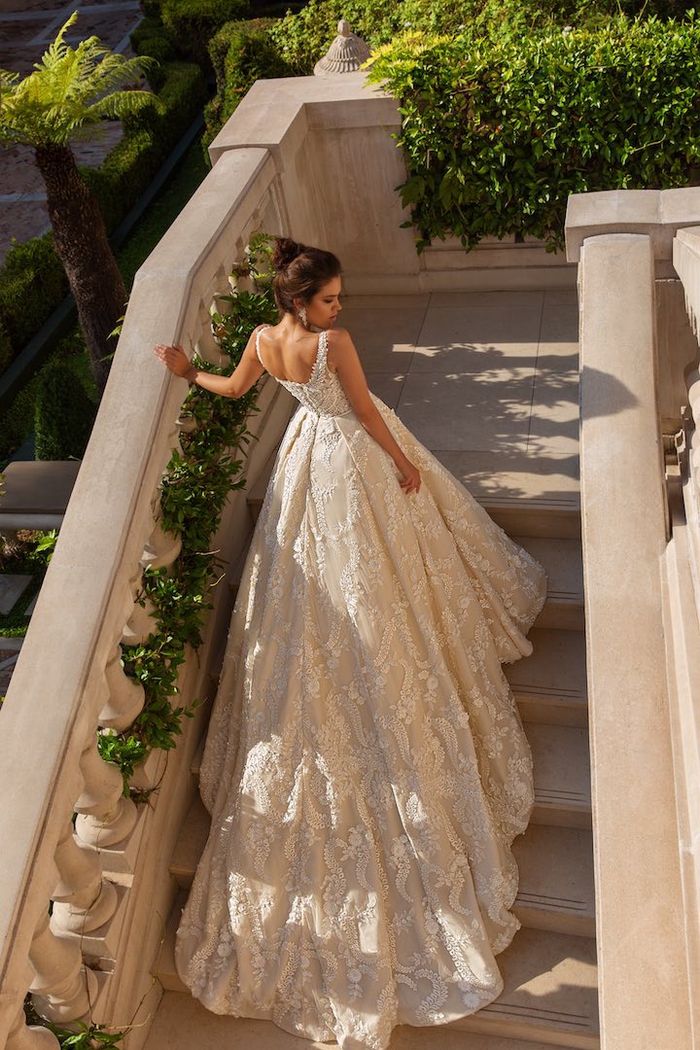Longue robe de mariée bustier princesse avec longue traine, belle femme en blanc robe dentelle photo sur les escaliers d'une résidence